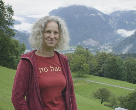 Tanja Moser steht auf einer Wiese vor einer alpinen Landschaft